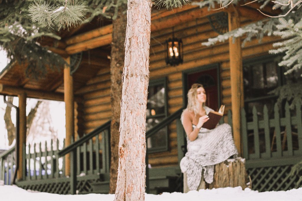 reading a book outside a cabin